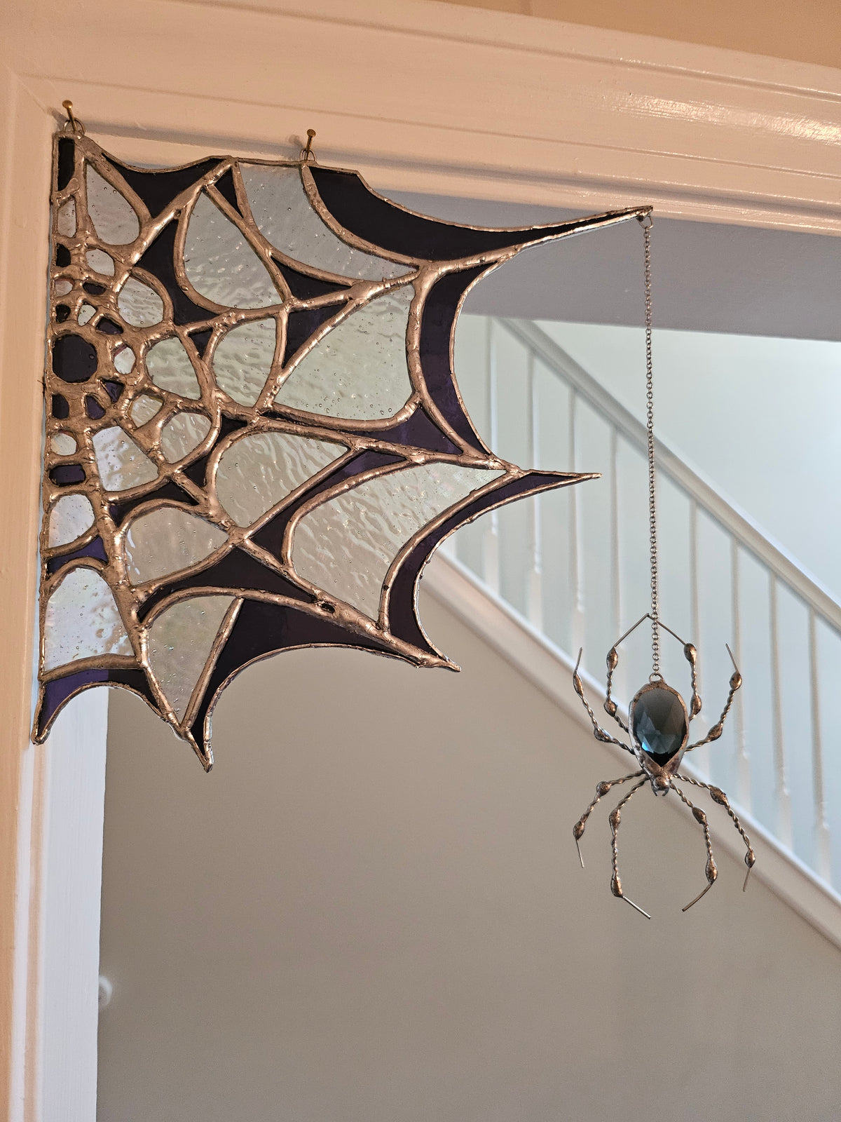 The Amethyst Web: Tiffany-style stained glass spider web suncatcher in amethyst and opalescent glass with a dangling glass-gem spider